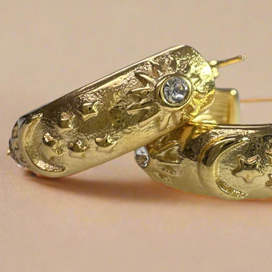 A pair of gold-plated stainless steel hoop earrings with intricate celestial designs and sparkling cubic zirconia accents.